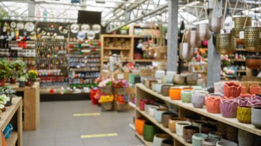 Bulanık çiçekçi vitrininde canlı saksılar ve çiçek aranjmanlarıyla çeşitli ev ve bahçe ürünleri sergileniyor..