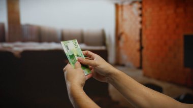 Kentsel inşaat sahasında Norveç kronu sayan bir adam, iş, finans ve kapalı alanda yatırım kavramlarını gözler önüne seriyor.