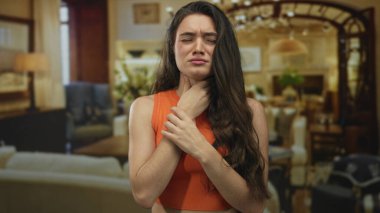 Geniş bir otel binasının içinde boğazını sıkan genç İspanyol kadın şiddetli bir acı içinde irkiliyor..