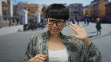 Vatikan San Pedro Meydanı 'nda el sallayan, gözlüklü, bulanık şehir manzarasına karşı duygularını ifade eden bir kadın..