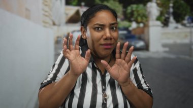 Çizgili formalı kadın hakem, şehir caddesinde trafiğin yoğun olduğu saatlerde çıplak ellerini kaldırıyor..