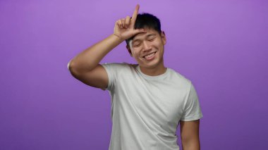 Beyaz gömlekli genç adam, izole edilmiş mor arka plana el hareketi yapıyor. Duygularını neşeli bir şekilde ifade ediyor..
