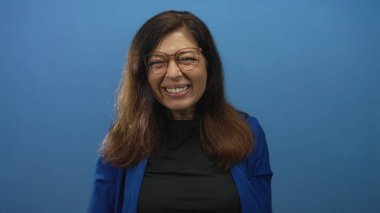 Stüdyoda orta yaşlı, gözlüklü ve parmaklarıyla yanaklarını iten bir kadın..