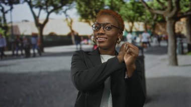 Genç Afro-Amerikalı kadın taştan kaldırımlar ve bej binalarla başparmaklarını geriye doğru uzattı..