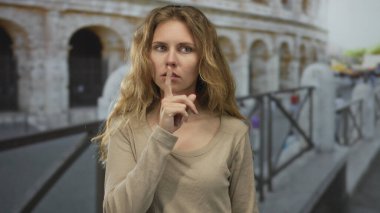 Kadın, İtalya Roma 'da sessiz bir an için parmağını kaldırır. Genç sarışın bir gezgin, sıradan bir portrede dudaklarını bastırır ve saçlarını savurur..