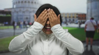 Gülümseyen genç bir kadın İtalya 'daki sidik kulesinin yanında sevinç ifade ediyor, açık şehir ortamında mutluluk ve heyecan sergiliyor..