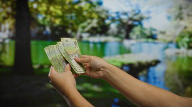 Bir şehir parkında Şili pesolarını sayan eller, serinletici güneş ışığı altında açık havada yapılan yatırım ve iş anlaşmalarının bir sahnesini akla getiriyor.