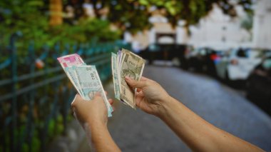 Kentsel caddede elleri olan Hintli banknotları sayan adam, açık şehir ortamında iş ve mali işlemleri sembolize ediyor..