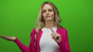 Yeşil arka planda elleri olan pembe hırka giyen bir kadın, tasvip ya da tefekkür etme ifadelerini sergiliyor..