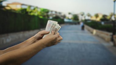 Şehir caddesinde elinde Polonya zloti banknotları tutan bir adam, açık bir gökyüzü zeminli bir şehir ortamında para ve finansman sergiliyor..