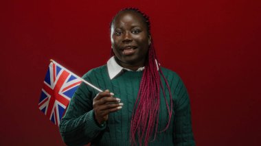 Kızıl arka planda Birleşik Krallık bayrağını tutan örgü örgülü bir kadın, İngiltere 'de ulusal gururunu sergileyen Afrikalı bir Amerikalı var..