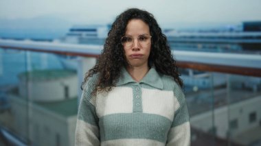 İspanyol kadın bir yolcu gemisinin güvertesinde, deniz kenarında, arka planda, gözlüklü ve çizgili kazaklı, sakin bir açık hava seyahati anı yakalıyor..