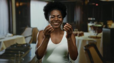 Lokantada gülümseyen bir kadın para harcayan, neşe ve güven saçan bir jest yapıyor..