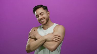 Sakallı genç bir adam beyaz bir atlet giyiyordu. Kollarını uzatarak canlı mor bir arka plana doğru gülümsüyordu. Hoş geldin enerjisi ve arkadaşlığı yakalıyordu..