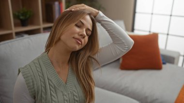 Binada koltukta otururken alnına elinle dokunan sarışın kadın, rahatlama..