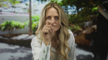 Odaklanmış bir portredeki bir sarışın olarak merakla dinlerken kadın elini cama vuruyor..