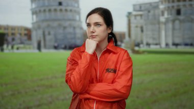 Turuncu hapishane tulumlu kadın, Pisa 'nın ikonik eğik kulesinin önünde durup esaret ve tarihi özgürlük arasında çarpıcı bir tezat oluşturuyor..