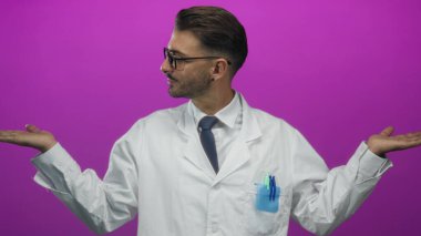 Gözlüklü ve beyaz önlüklü bir bilim adamı mor bir stüdyoda avuç içi kaldırıyor..