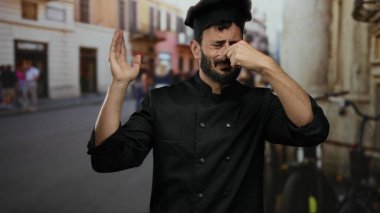 Siyah üniformalı İspanyol aşçı sokak ortamında burnunu çimdikliyor..