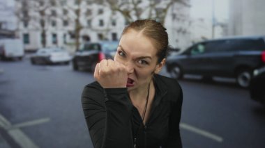 Kadın çalıştırıcı, şehir caddesinde siyah ceketli ve ıslık çalan arabaların yanında parmağını işaret ediyor; kararlılık.