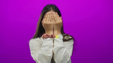 Kırmızı gözlüklü genç bir kadın ve zarif beyaz bir bluz bir stüdyoda elleri ile yüzünü örtüyor..