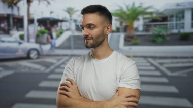 Kentin arka planında ağaçlarla güvenli bir şekilde duran genç adam berrak gökyüzünün altında hareketli bir şehirde rahat bir tavır sergiliyor..