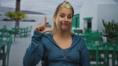 Açık hava terasında beyaz binayı gösteren kadın parmağı parlak gün ışığı altında; şüphecilik.