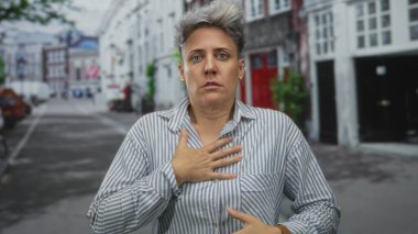 Meşgul şehir caddesinde, kısa saçlı, göğsünde çizgili tişört olan beyaz kadın binalarla doluydu..