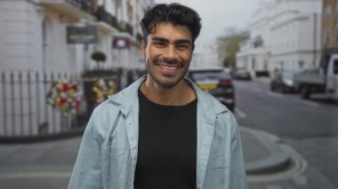 Genç İspanyol adam, Gürcü binalarıyla dolu hareketli bir şehir caddesinde iki eliyle dürbün hareketi yapıyor..