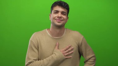 Erkek göğsünü arka plana doğru uzatırken, genç İspanyol erkek yeşil zemine samimiyet gösteriyor..