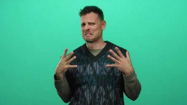 Genç adam, izole edilmiş yeşil arka plan duvarından tiksinerek tepki veriyor.