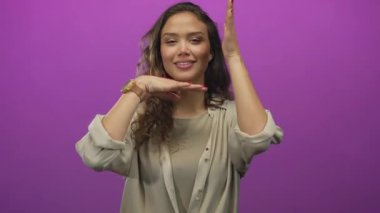 Parmaklarıyla sanal bir görüntü oluşturan bir stüdyo ortamında ellerini çerçeveleten bir kadın..