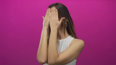 Genç İspanyol kadın yüzünü morumsu stüdyo duvarına karşı iki eliyle kapatıyor. Utanç gizliliği..