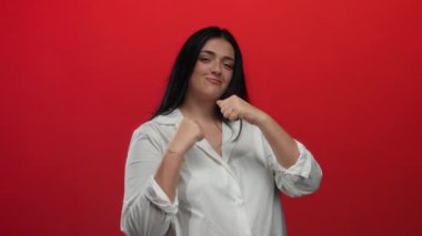 Cesur, kırmızı bir zemine karşı kendine güveni olan genç ve cüsseli bir kadın boks yapıyor. Güçlendirme ve kararlılığa odaklanıyor..