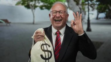 Takım elbiseli kıdemli bir adam elinde bir dolar işareti olan bir para çantası tutuyor, gülümsüyor ve sokakta iyi niyetini gösteriyor, başarı ve yozlaşma temalarını ima ediyor..