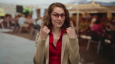 Restoran terasında gülümseyen bir kadın yüzünü gösteriyordu. Bulanık şehir sokak manzarası, doğal rahat duruş ve kahverengi gözlüklü bir kadın..