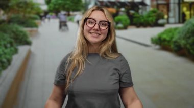 Gözlüklü bir kadın şehir sokağının dışında, çevrenin yeşilliklerle çevrili olduğunu ve neşeli bir ruh hali içinde olduğunu söylüyor..