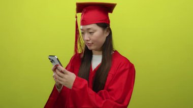 Kırmızı elbiseli bir kadın, elinde parlak sarı arka planda akıllı bir telefonla, güvenle gülümsüyor ve başarıyı ve başarıyı temsil ediyor..