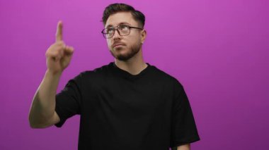 Sakallı beyaz bir genç, canlı pembe bir arka plana karşı olumlu bir jest yapıyor. İzole bir ortamda memnuniyetsizlik ya da hoşnutsuzluk gösteriyor..