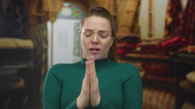 Kapalı halı dükkanında yeşil balıkçı yaka kazak giyen genç beyaz kadın özür diliyor..