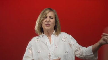 Kırmızı stüdyoda dans eden, gözleri kapalı, gülümseyen ve kollarını çeviren bir kadın, saf neşe..