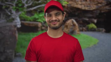 Kırmızı şapkalı ve gömlekli gülümseyen genç İspanyol bir adam ormanda el pençe divan öpüşen dudaklara; şefkat bağı sıcaklığı.