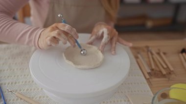 Kadın çanak çömlek atölyesinde elleri ile pürüzsüz küçük kilden kase şekillendirir; işçilik yaratıcılık sabrı odaklar.