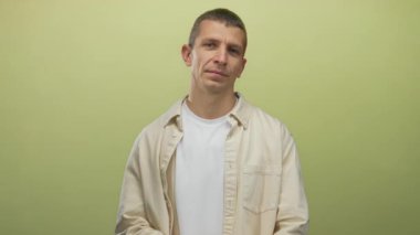 Sarı duvarın önünde kollarını kavuşturan beyaz bir adam izole edilmiş arka plan kapalı bej gömlekli, rahat bir ifade, sakin ve sakin bir tavır sergiliyor..