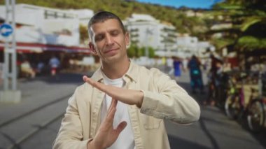 Bej ceketli adam kalabalık bir caddede, bulanık insanlar ve sokak arkası ile çevrili bir yerde mola veriyor, açık şehir sahnesinde bir anlık duraksama yaşıyor..