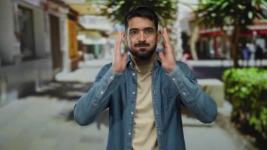 Şehir sokağında stresli görünen genç bir adam elleriyle yüzünü kapatıyor. Halka açık bir şehirde duygularını ve izolasyonu aktarıyor..