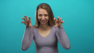 İzole edilmiş yeşil arka plana şakayla poz veren bir kadın anlamlı jestler yapıyor ve uzun saçlı, rahat bir gömlekle heyecan gösteriyor.