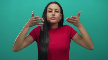 İzole edilmiş yeşil arka planda meditasyon yapan, kırmızı gömlekli, uzun siyah saçlı, sakin ve huzurlu bir ortamda odaklanan bir kadın..