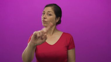 Kırmızı tişörtlü İspanyol orta yaşlı kadın stüdyoda parmağını ileri uzatarak bir işaret yapmıyor; reddediyor..