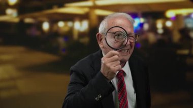 İş kıyafeti giymiş kıdemli bir adam elinde büyüteçle dışarıda dolaşarak soruşturmayı ya da detektifliği sembolize ediyor..